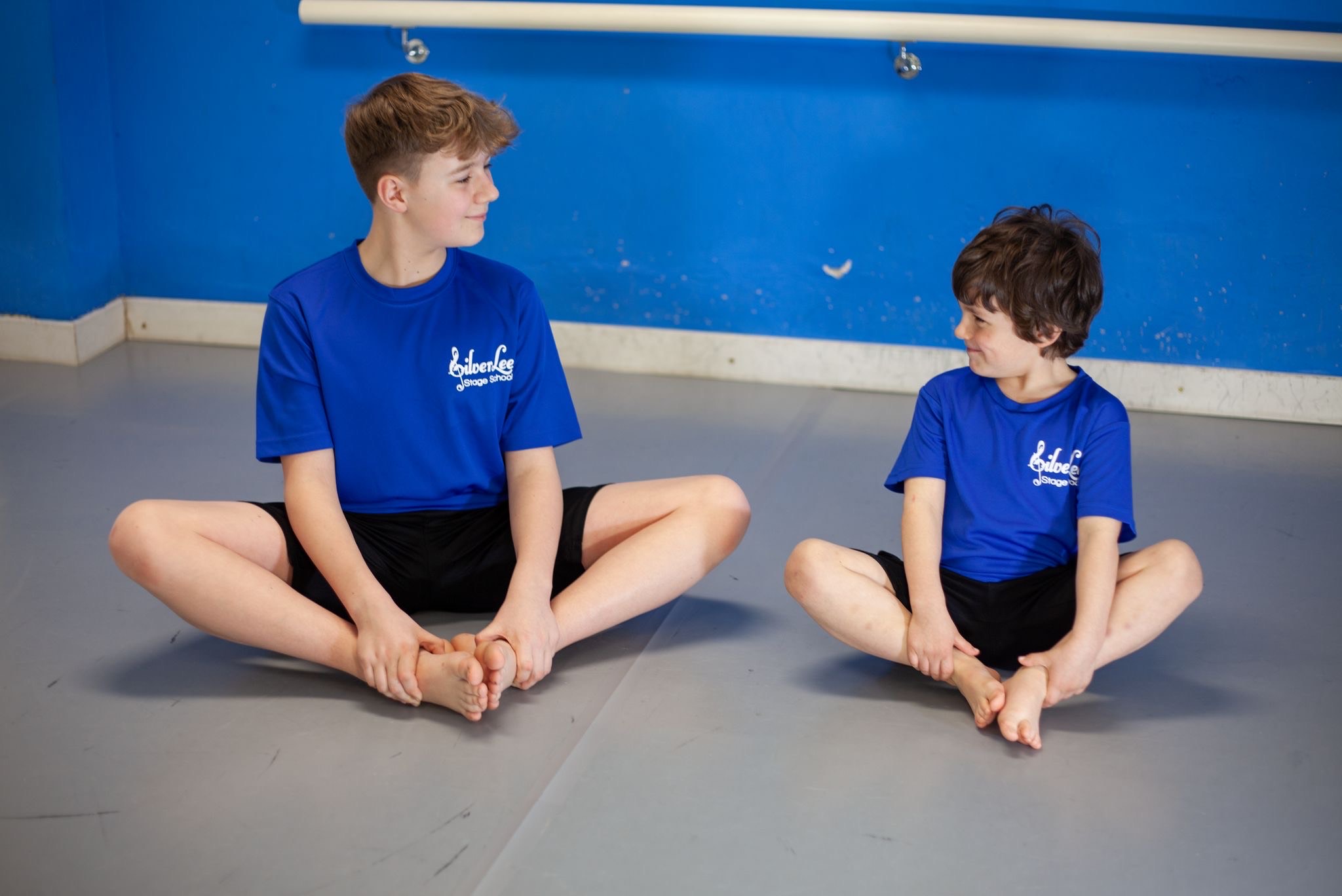 An older and a younger boy stretching together at SilverLee Stage School